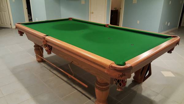 Angled view showing full table length with turned leg design and felt surface