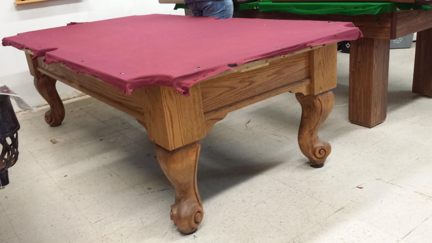 Side profile of pool table displaying pink playing surface and decorative leg design