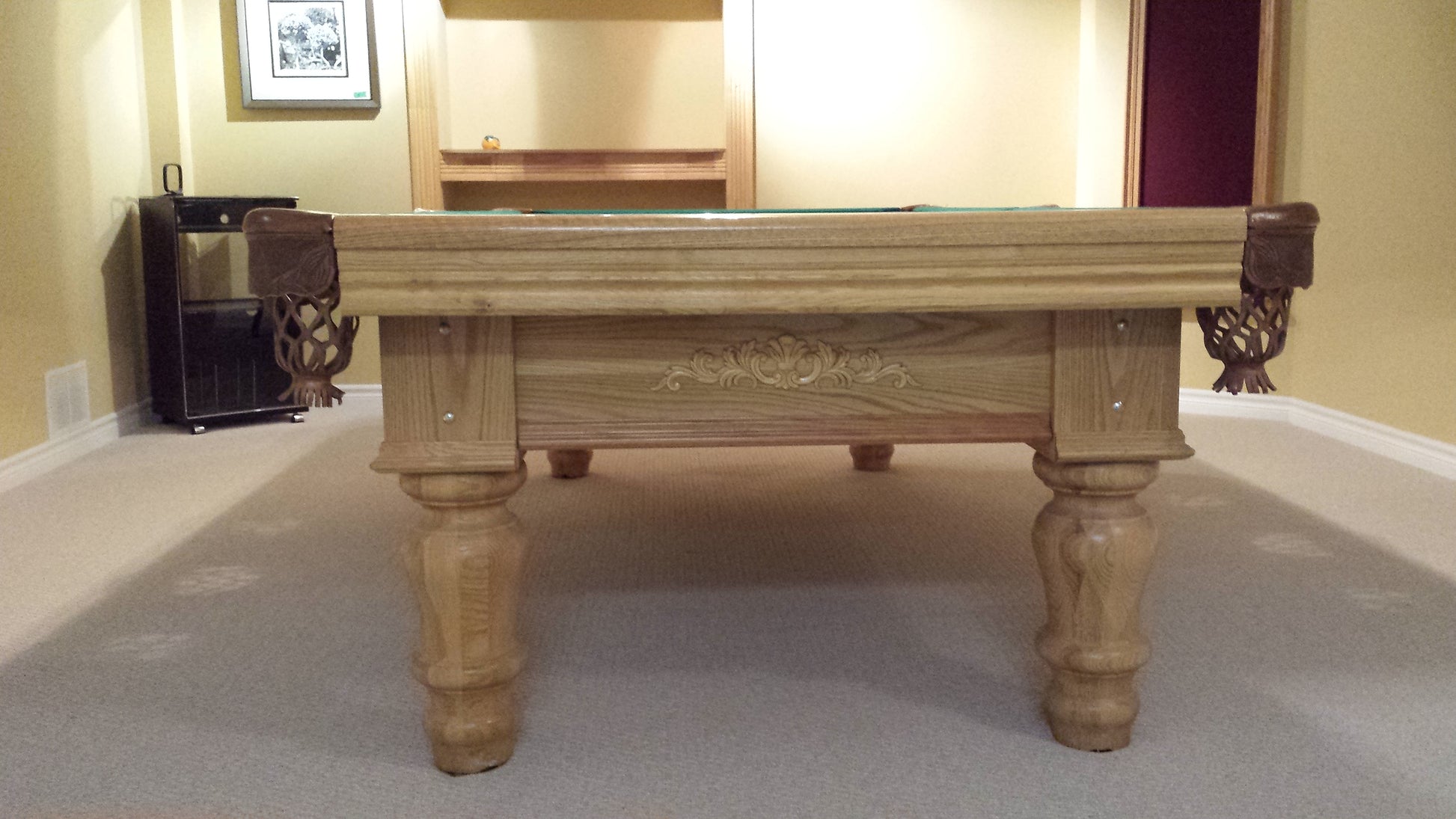 End view of billiard table showing carved wood rail and corner pocket