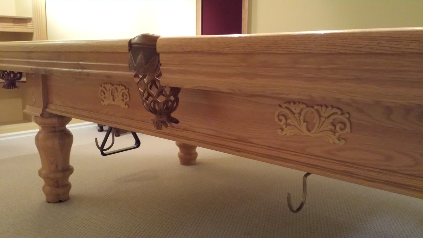Side rail showing decorative wood carvings and ball return mechanism