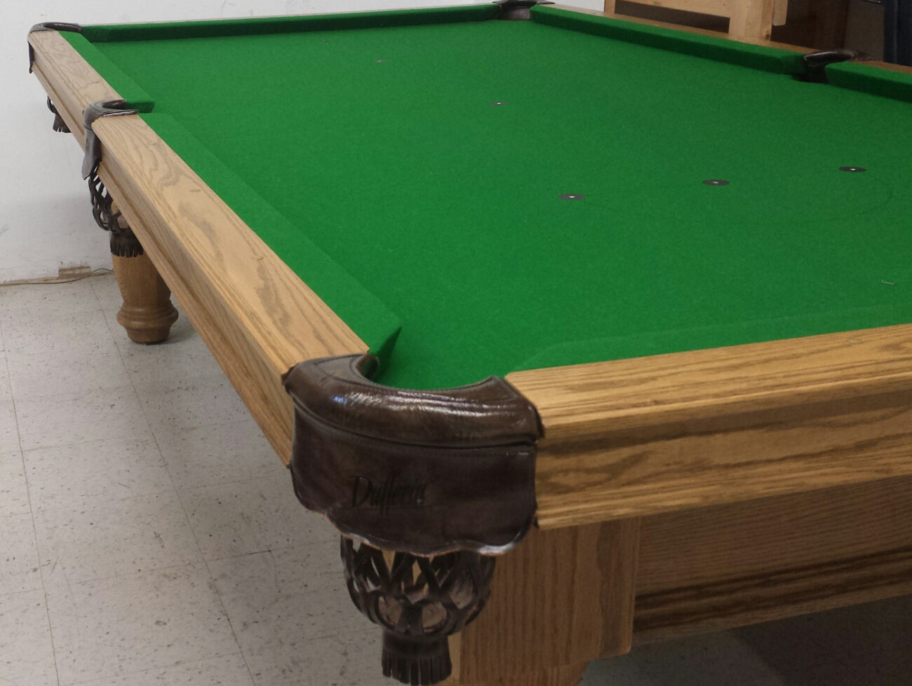 Corner pocket detail with dark leather and ornamental wooden leg