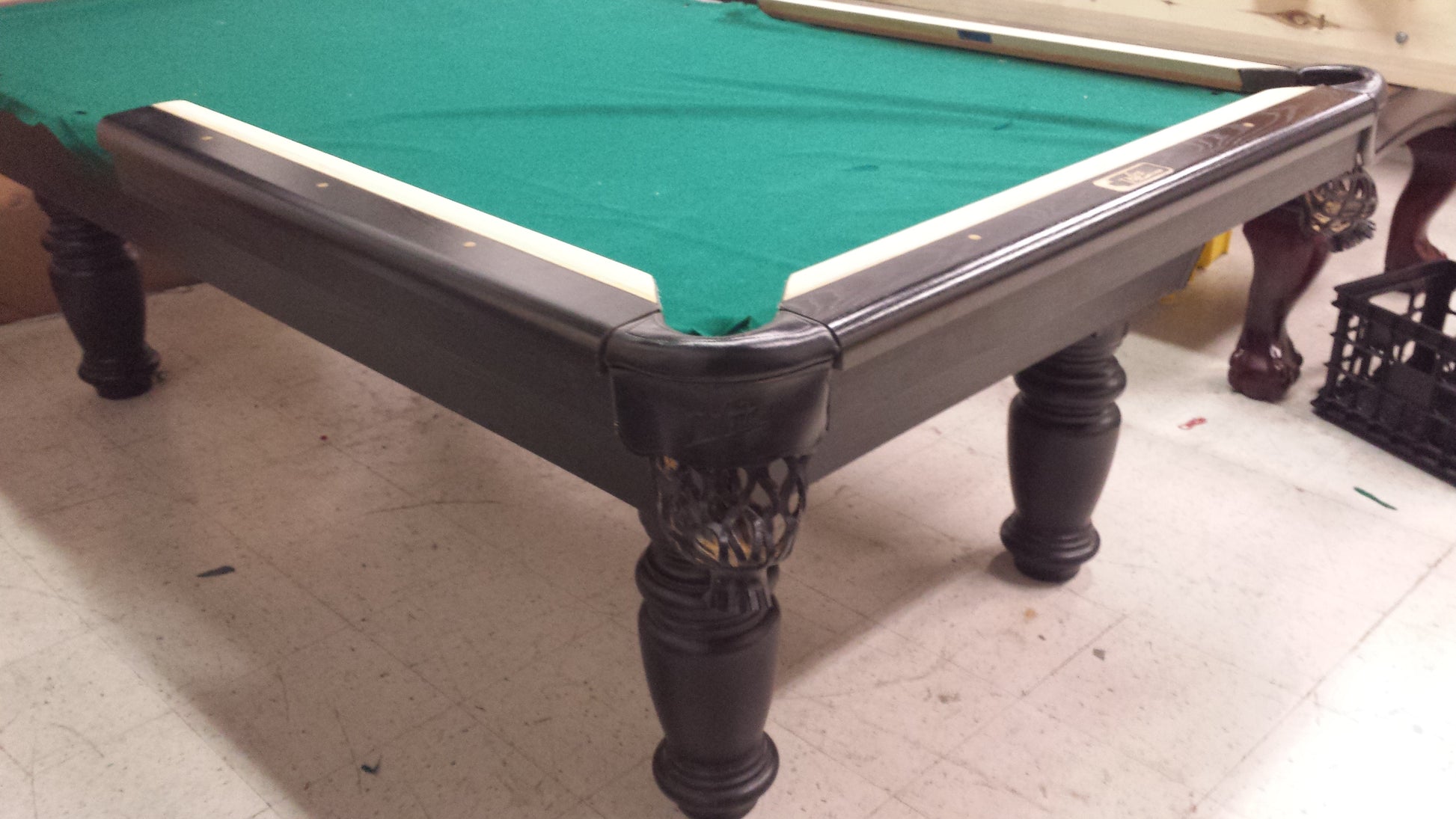 Angled view of billiard table showing corner pocket and turned leg details