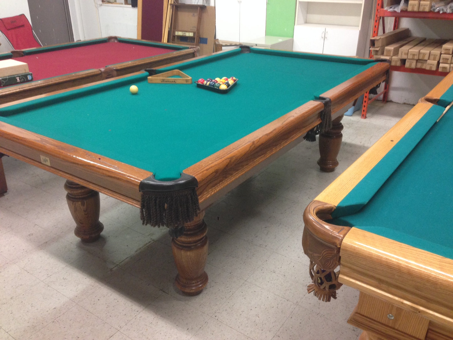 Adjacent billiard tables with turquoise felt and carved wooden legs