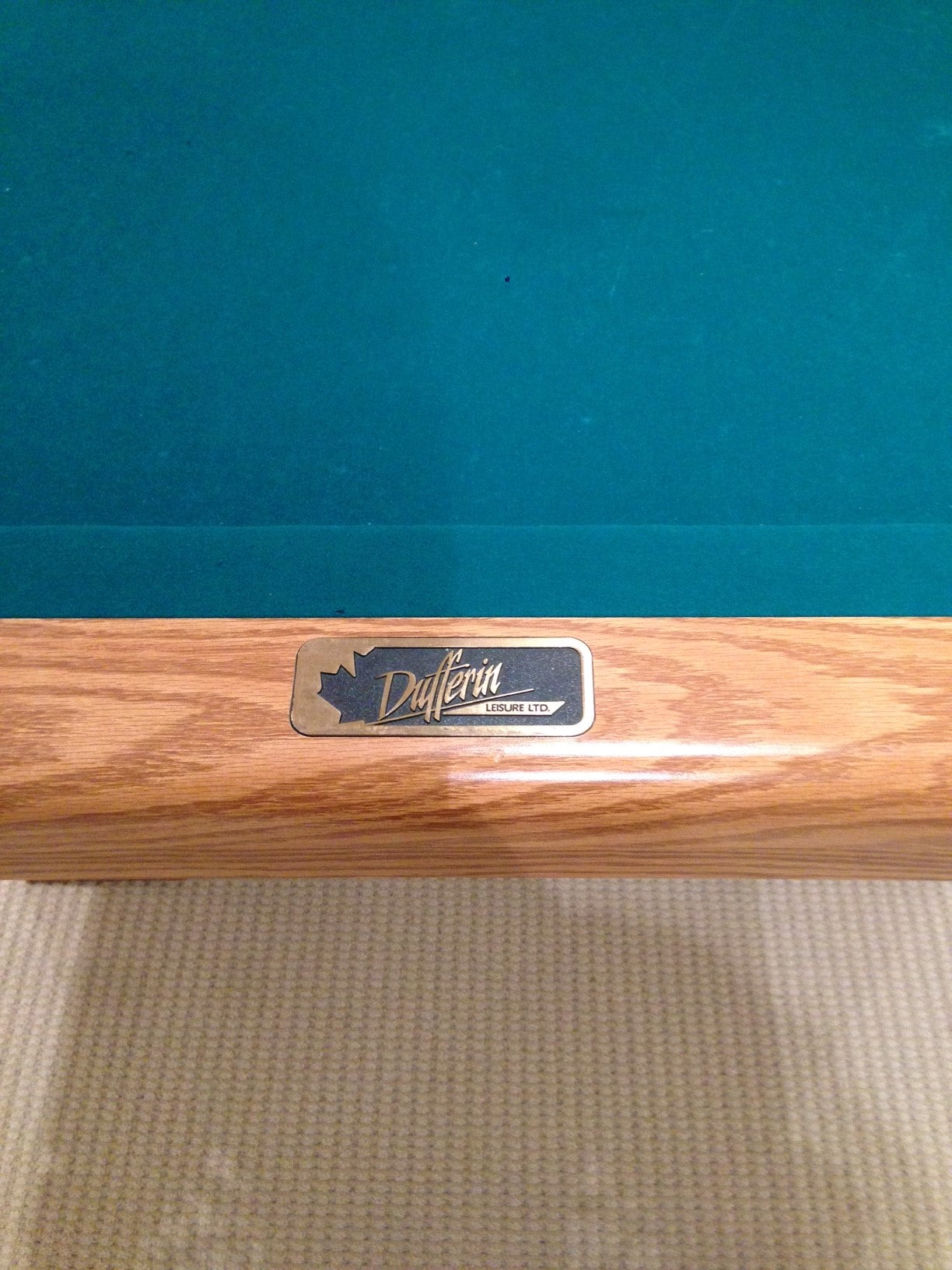 Close-up of rail nameplate and teal felt surface meeting wood rail