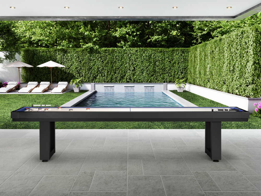 Angled perspective of shuffleboard table under pergola with pool backdrop