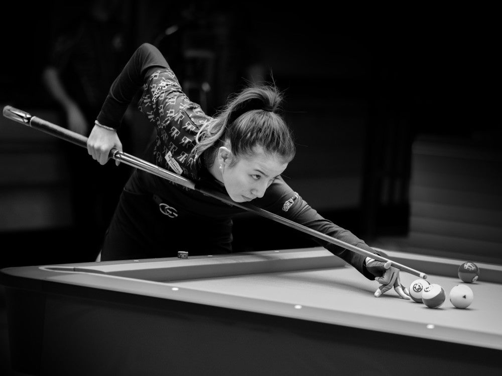 Player intensely focusing on a shot during a billiard game.