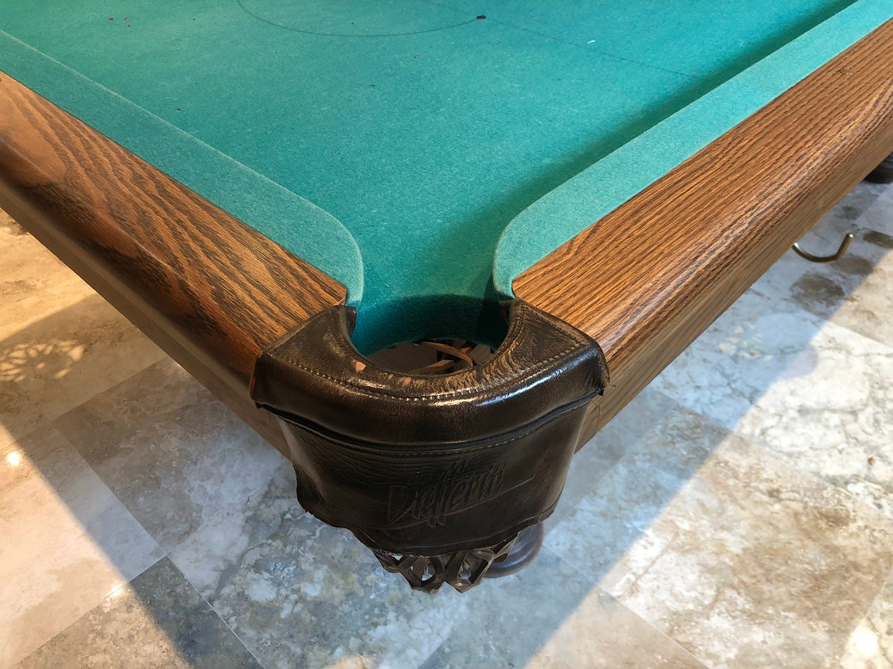 Close-up of corner pocket with leather facing and wooden rail trim detail