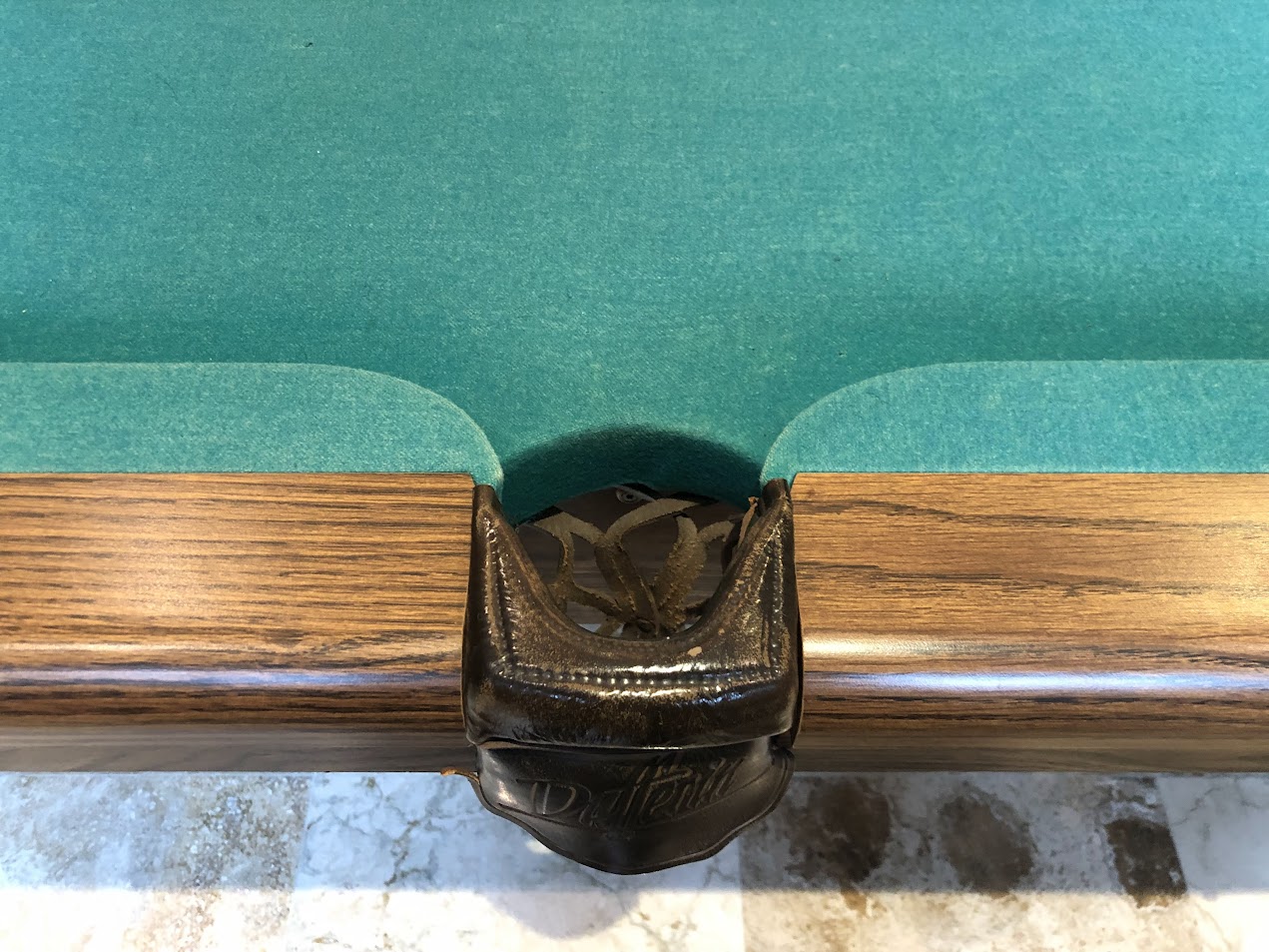 Leather pocket detail with ornate metal ring and felt edge binding